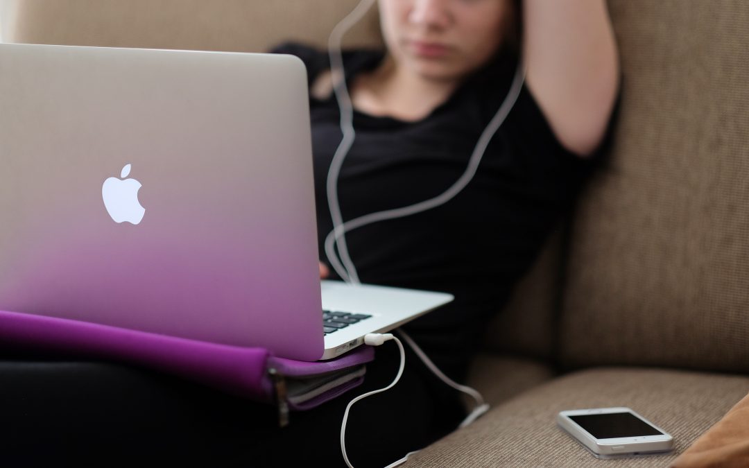 woman sitting with a purple laptop and headphones in