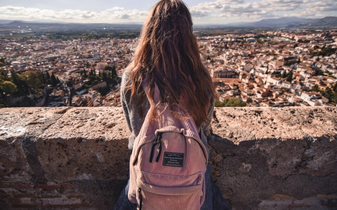 teen standing along a stone wall looking out at a city