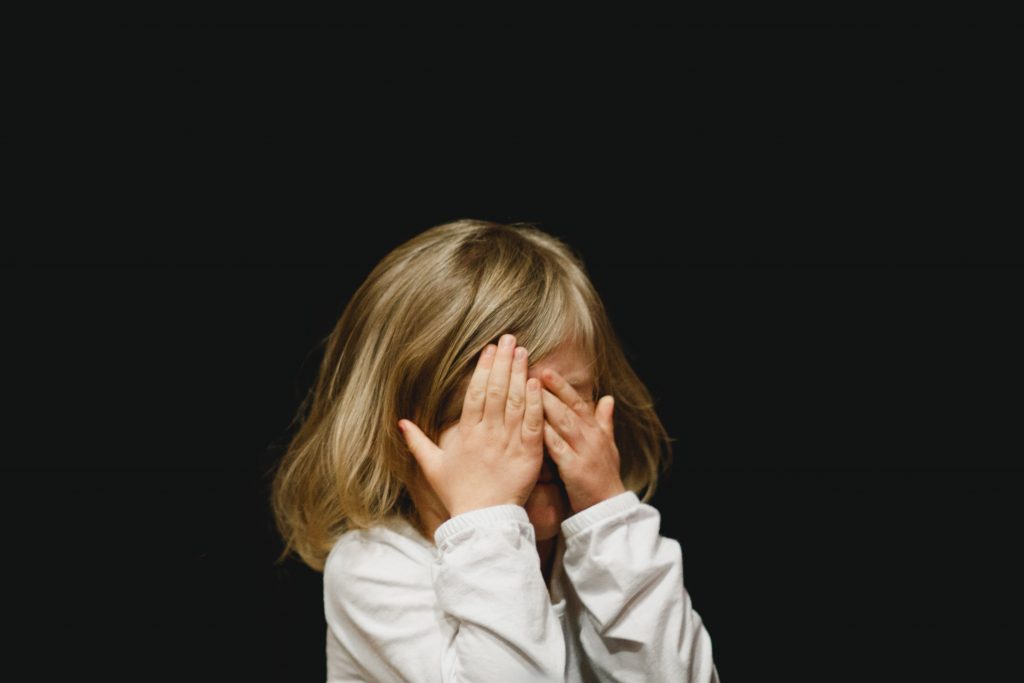 little girl crying and covering her face