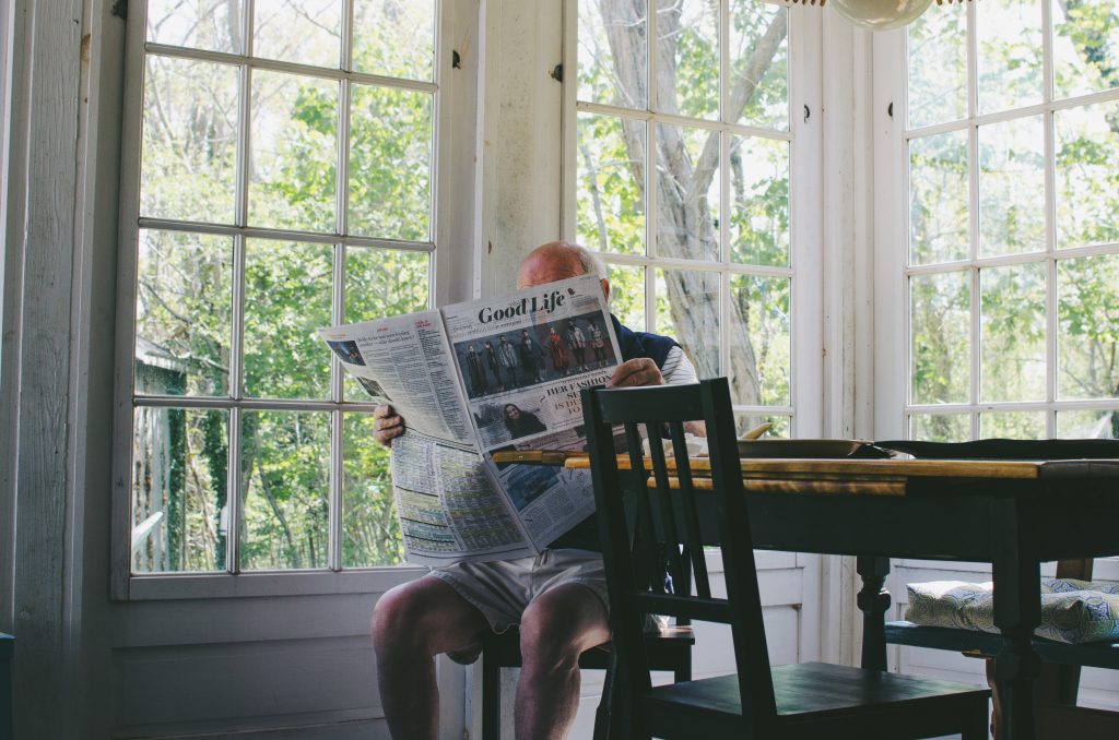 old man sitting and reading the newspaper