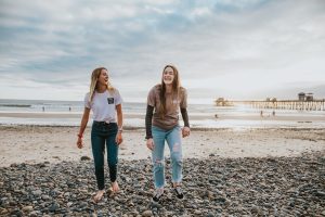 two women enjoying and walking on the beach