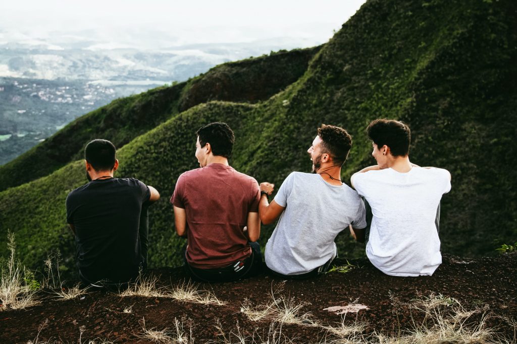 A cogroup of men sitting on a ledge laughing together