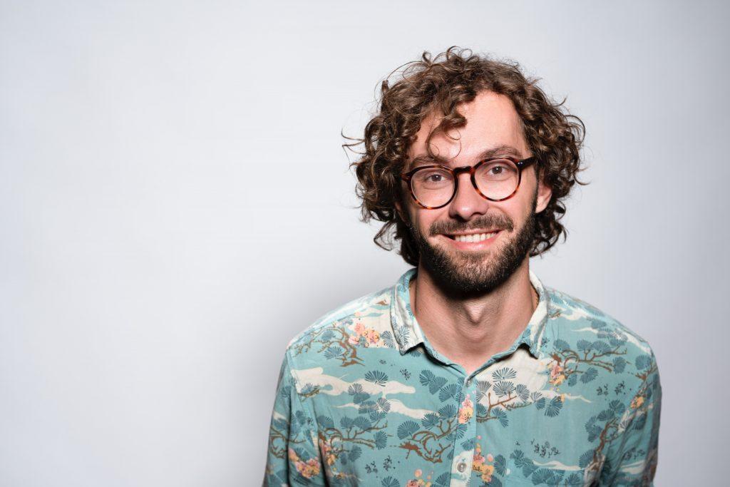 man in blue shirt wearing glasses with curly hair 