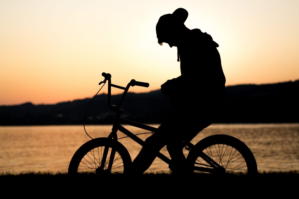teen on a bicycle in front of a sunset 