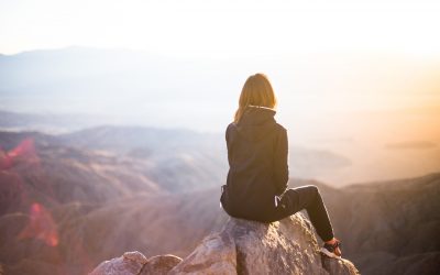 woman sitting on the cliff and looking at the moutains far away