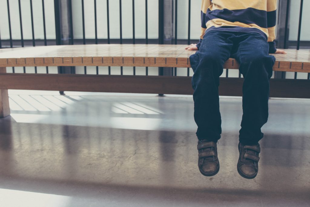 boy wearing brown shoes sitting on wooden bench