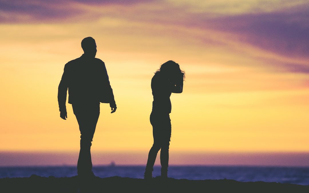 man walking after a woman crying in front of a sunset