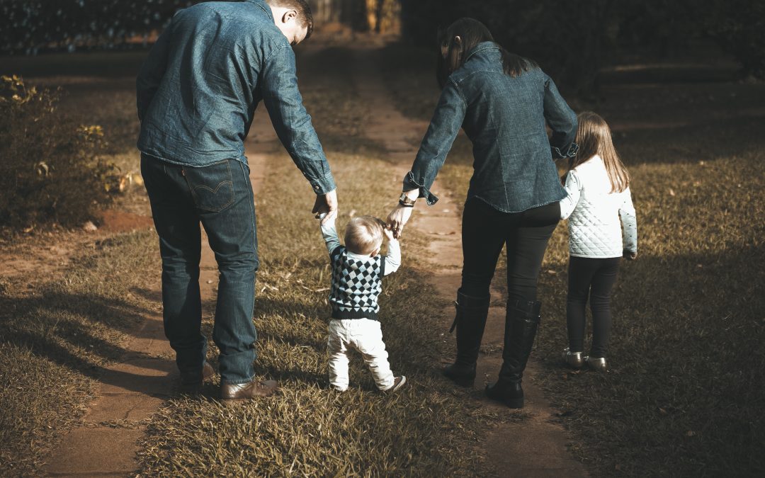 parents holding hands while walking with their two children