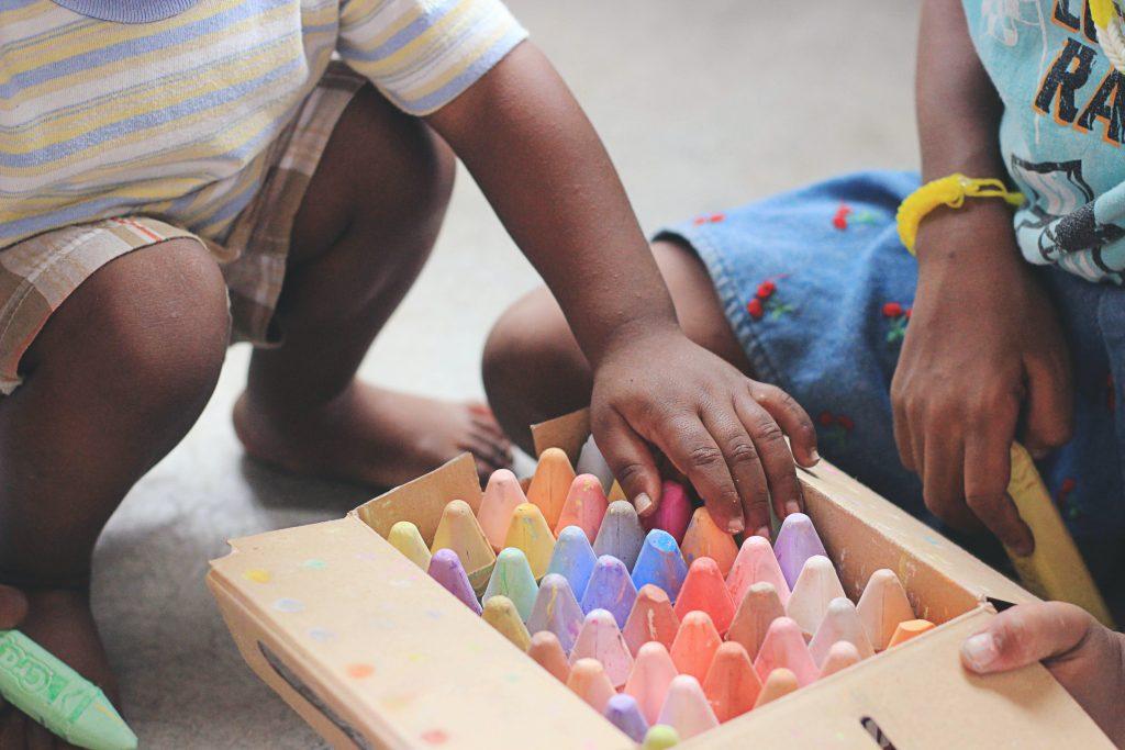 children choosing chalk out of a box on the ground 