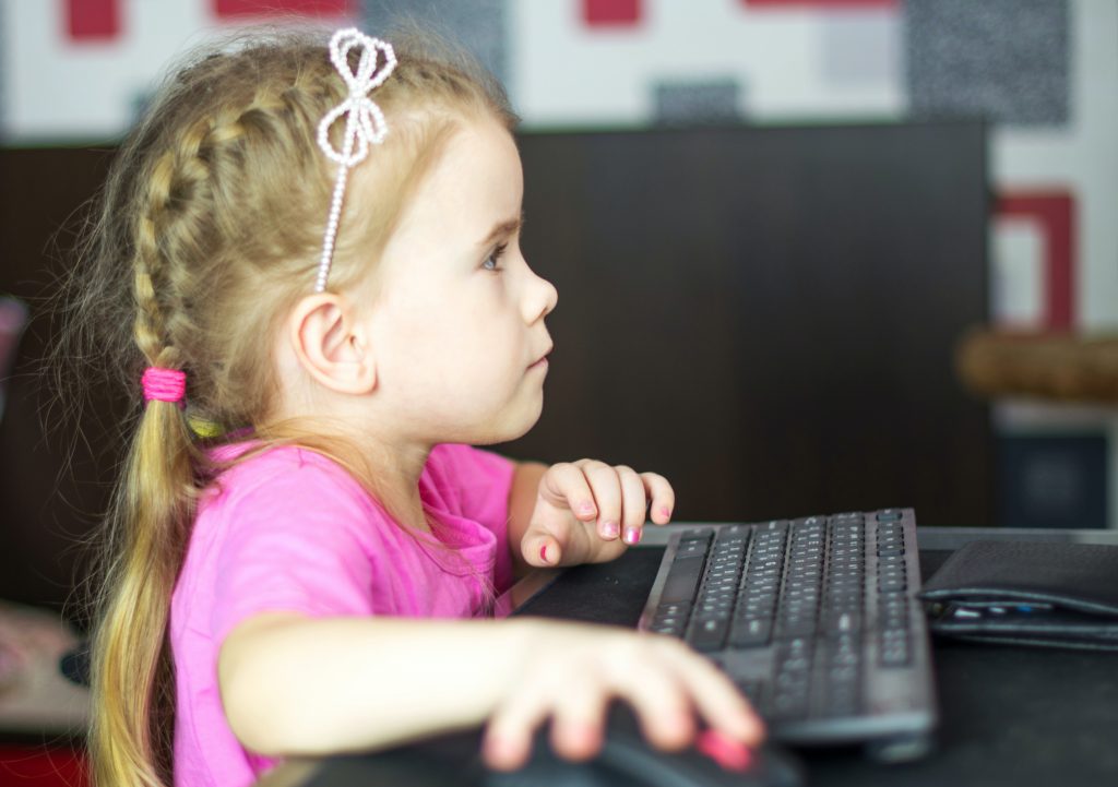 child holding the mouse of a computer 