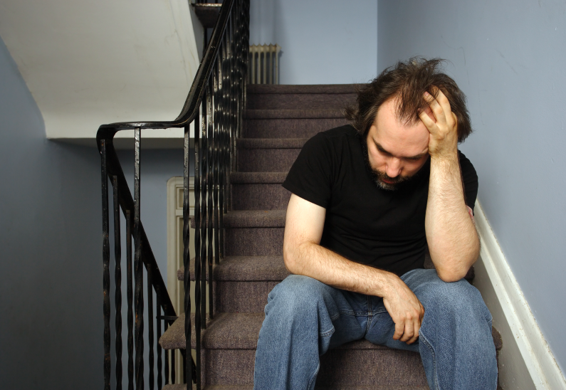 man sitting on the stairs with his hand on his head