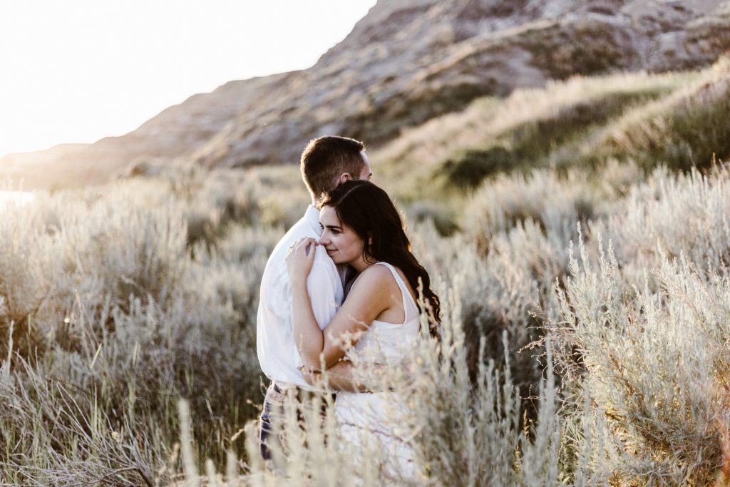 couple smiling and hugging each other in a field