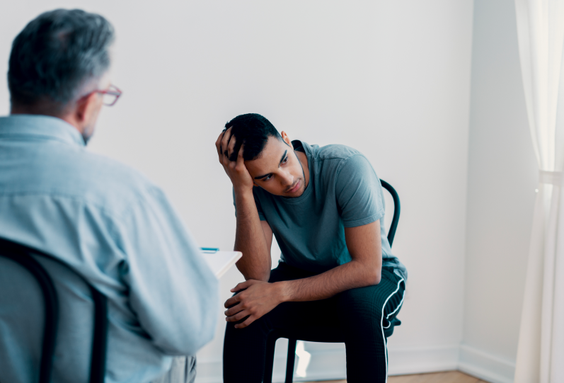 man sitting in front of a psychologist holding his head