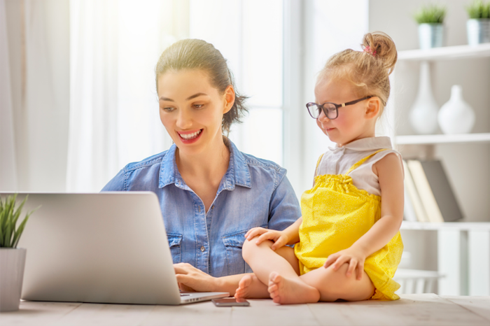 happy mom and toddler with glasses looking at a laptop