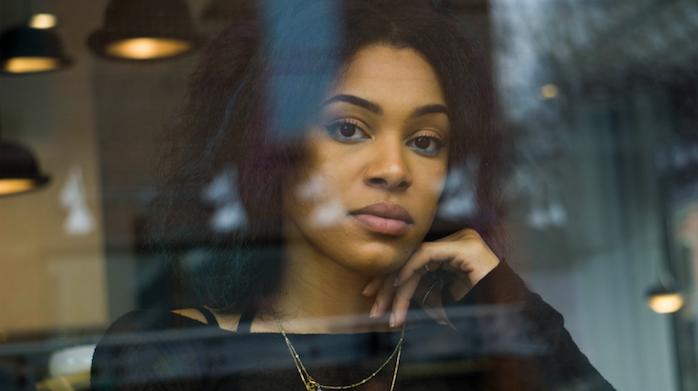 woman with black hair looking out a window.
