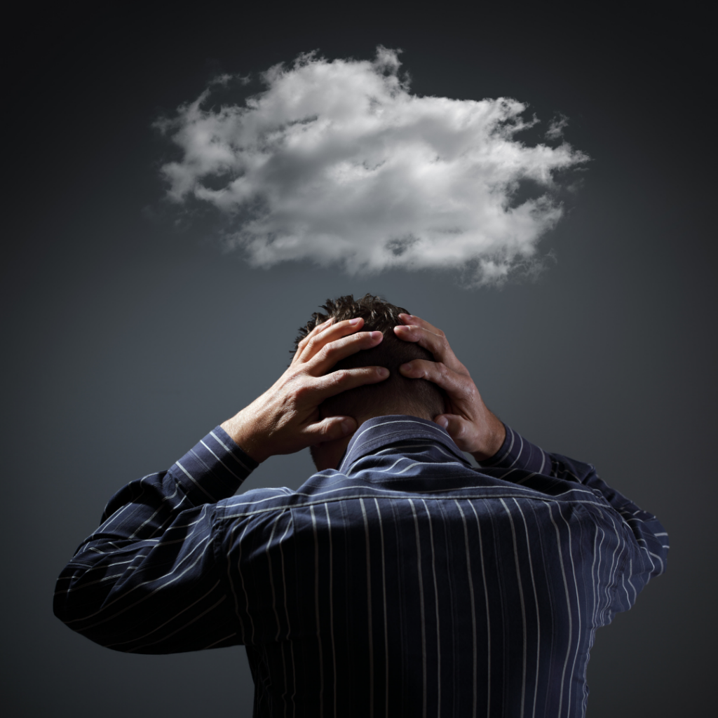 man holding his head with clouds floating over his head