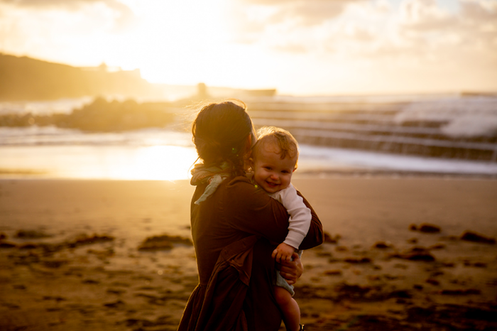 woman holding her baby standing near shore