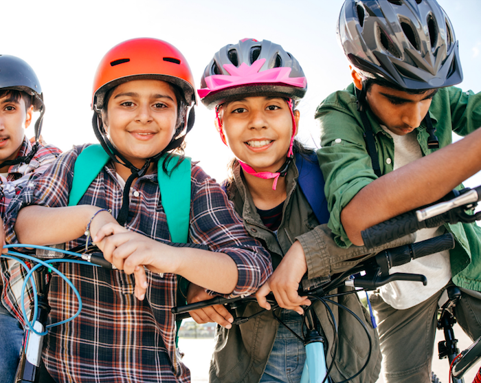 group of kids wearing safety gear on head and holding their bicycle 