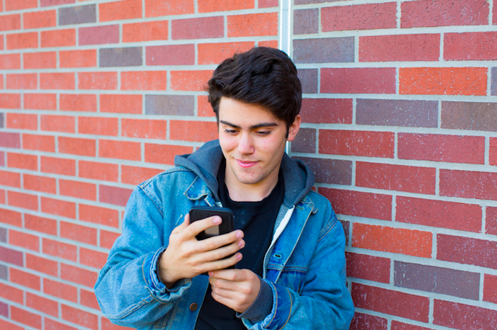 handsome man wearing denim jacket and looking at his phone