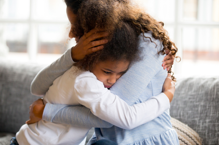 woman hugging a young girl with curly brown hair 