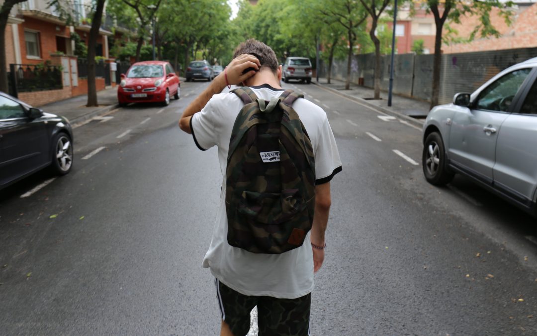 teen coming back from the classes with his hand on head and wearing backpack