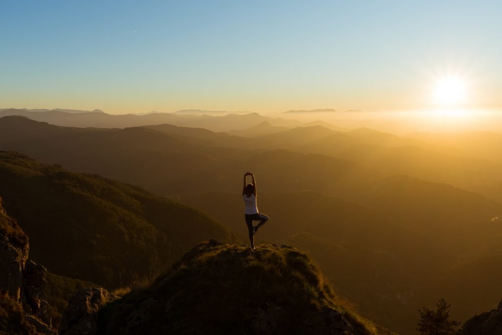 woman doing yoga pose and stnading on a cliff