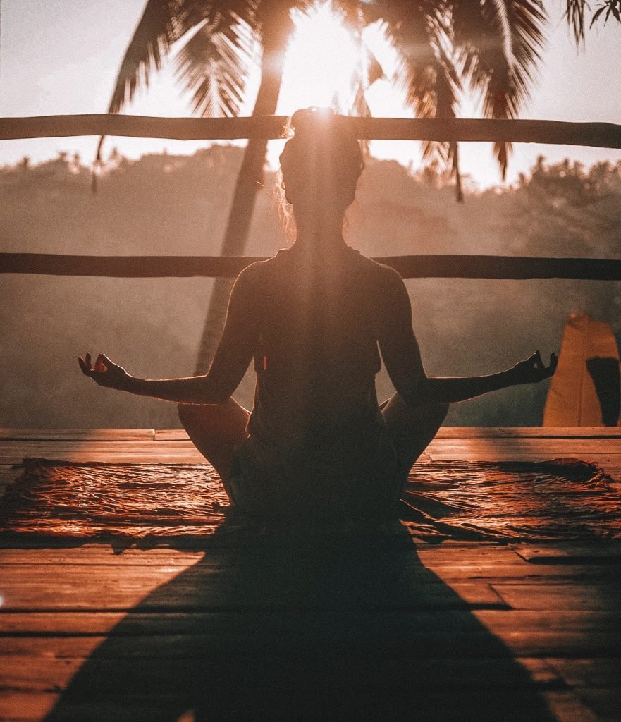 woman doing meditation while facing sun