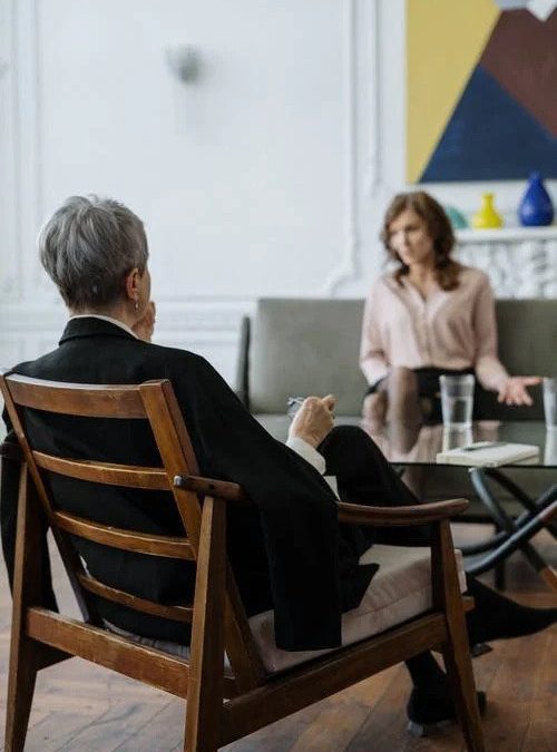 therapist with back to the camera sits listening to their client.