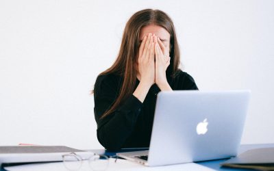 woman with hands on her face by laptop