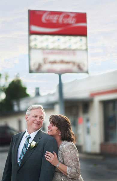 older couple dressed up and posing in front of a diner