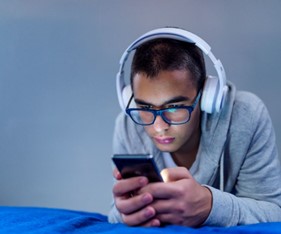 a boy wearing headphones using a cell phone
