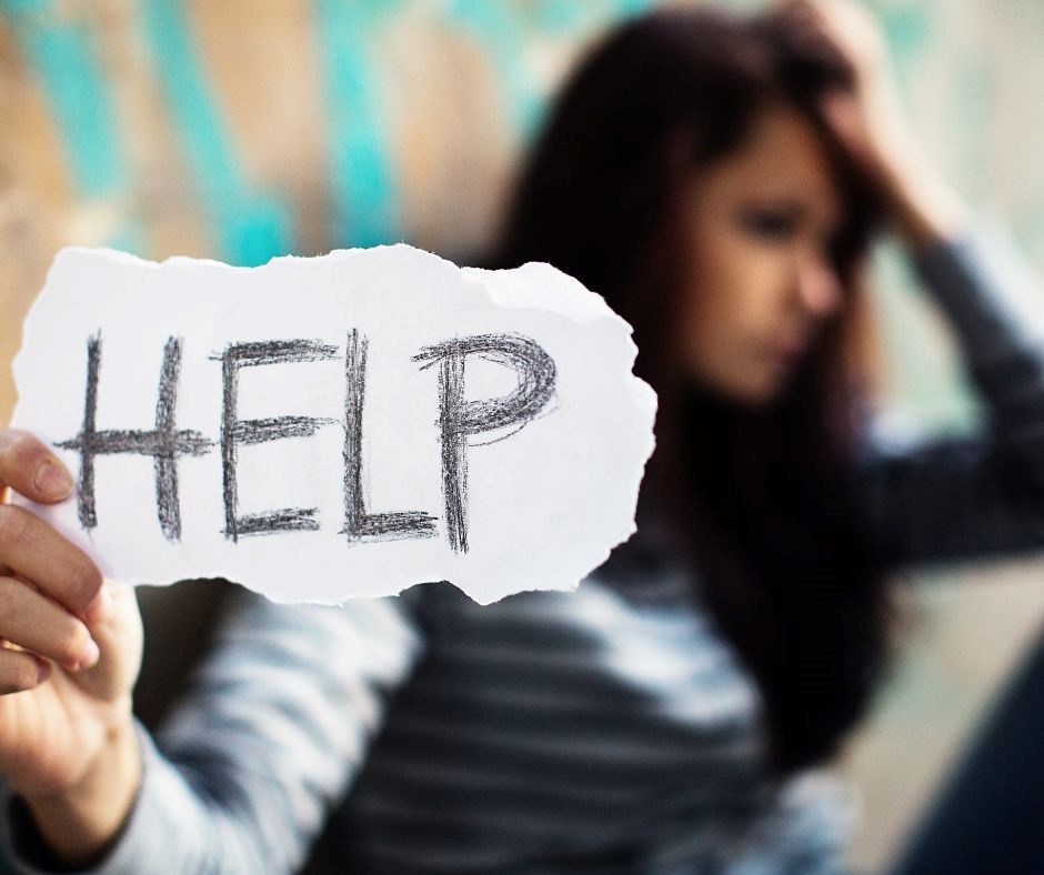 Girl with her hand on her head holding up a piece of paper that says help. 