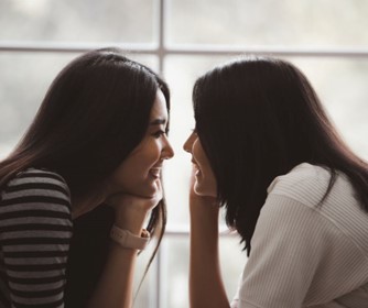 two women looking into each other's eyes smiling 