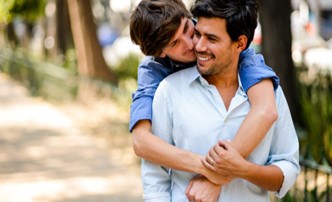 man wrapping his arms around the back of another man smiling