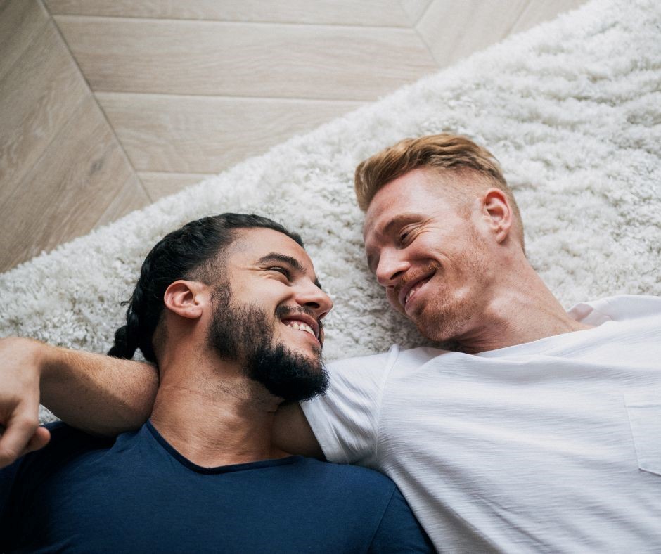 two men lying on the ground embracing and smiling