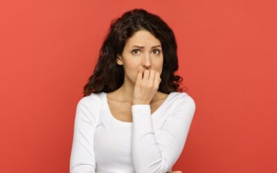 A woman covering her mouth with her hand against a red background