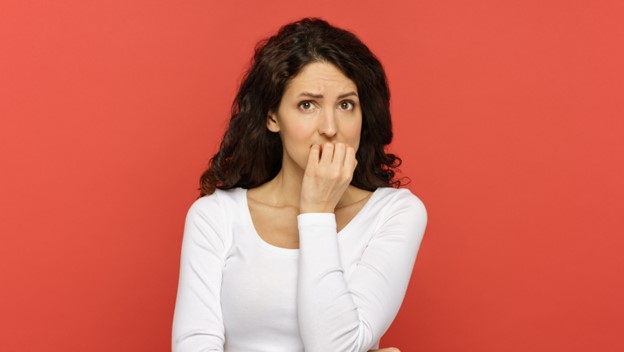 A woman covering her mouth with her hand against a red background