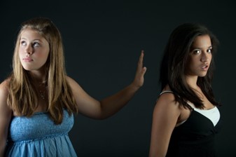Two young women standing in front of a black background.