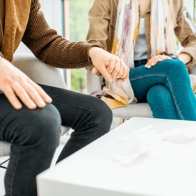 A man and woman sitting on a couch holding hands