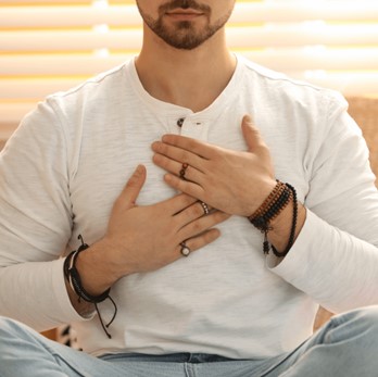 A man meditating with his hands on his chest.