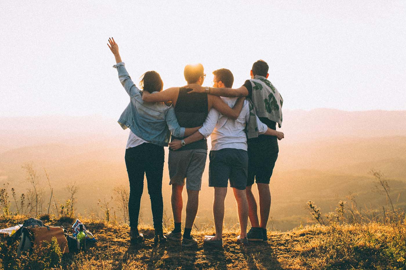 Image of a multiple people standing on top of a cliff with their arms around each other's shoulders as the sun goes down. Learn to embrace your spirituality with the help of spiritual therapy in Simi Valley, CA.
