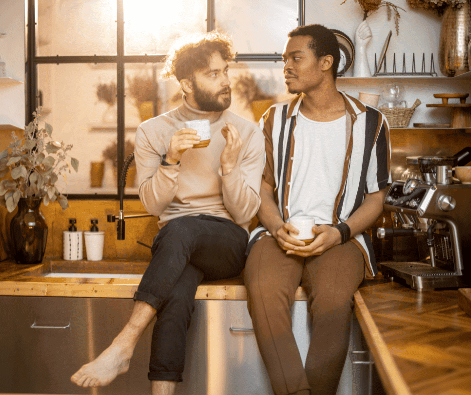 two men sitting on a counter with cups of coffee