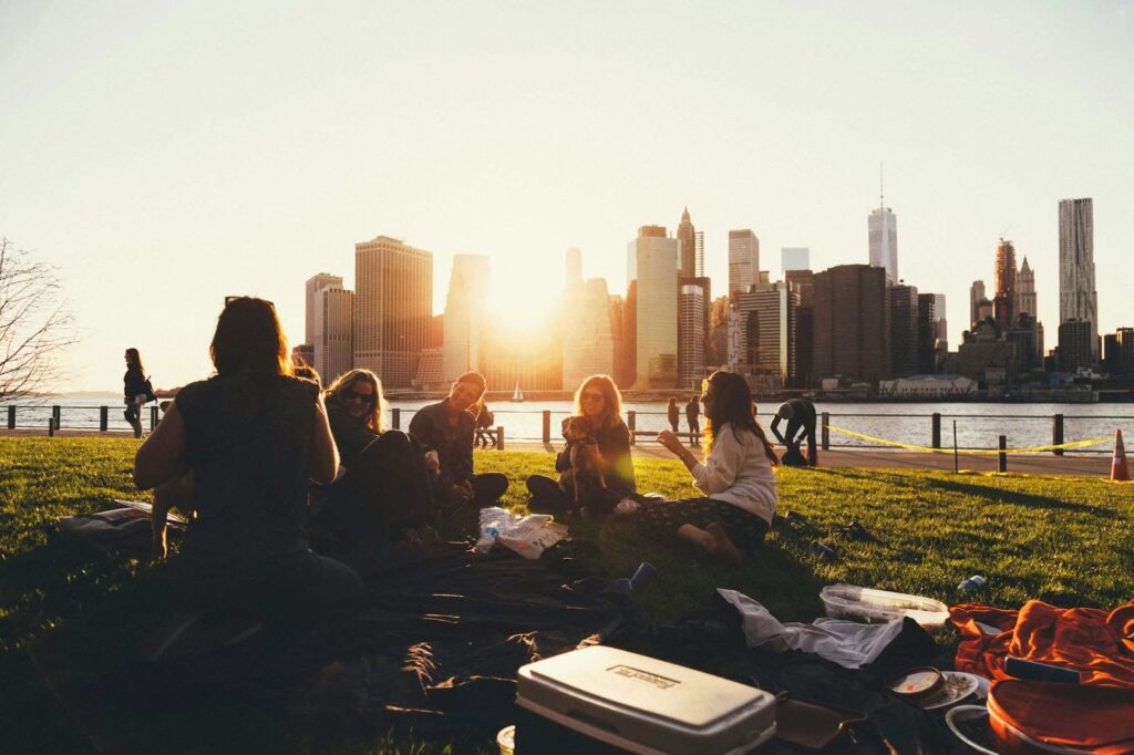 a group of people sitting on grass in front of a city skyline