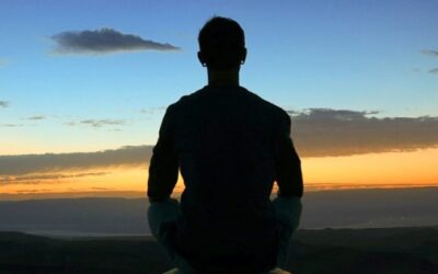 A silhouette of a person meditating at sunset