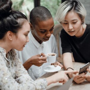 Three women of diverse ethnicities engaged in a conversation at a café table