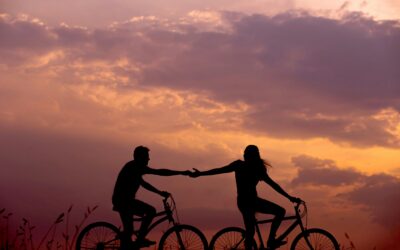 A couple biking holding hands together