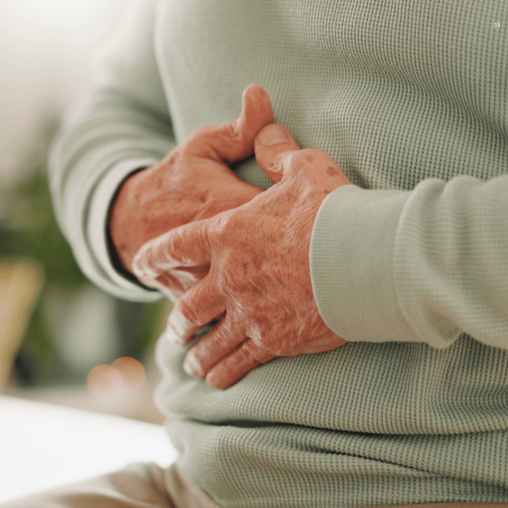 A man grimaces while holding his stomach, indicating he is experiencing significant abdominal pain.