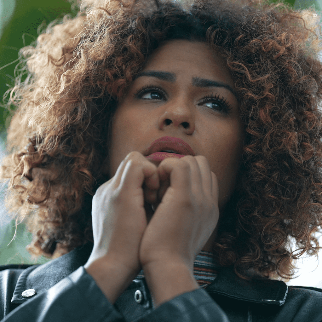 A woman with curly hair wearing a stylish leather jacket, exuding confidence and modern fashion sense.