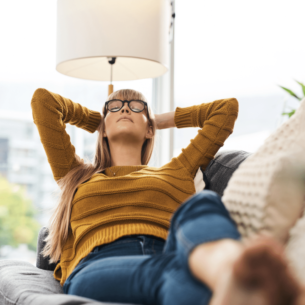 A woman with glasses is comfortably relaxing on a couch, enjoying a moment of leisure in a cozy setting.