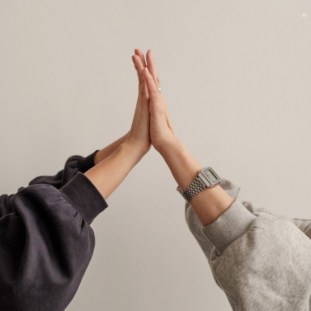 Two People Wearing Sweatshirts and Watches High-Five